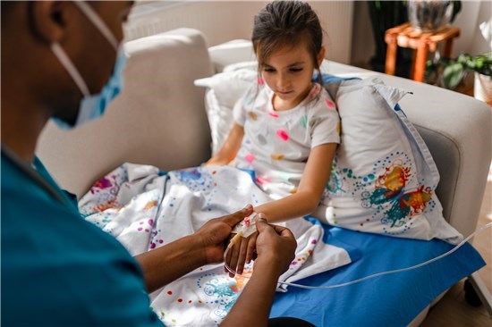 Girl receiving IV from doctor on couch