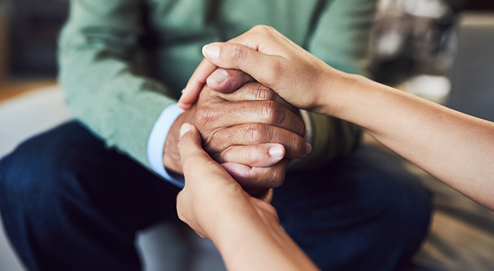 Picture of a clasped hand being enveloped by another hand