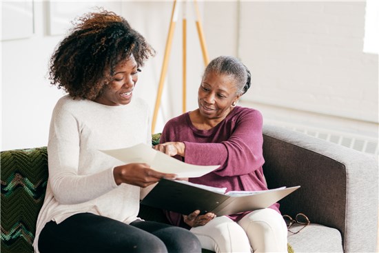 Two women on couch looking at and discussing documents