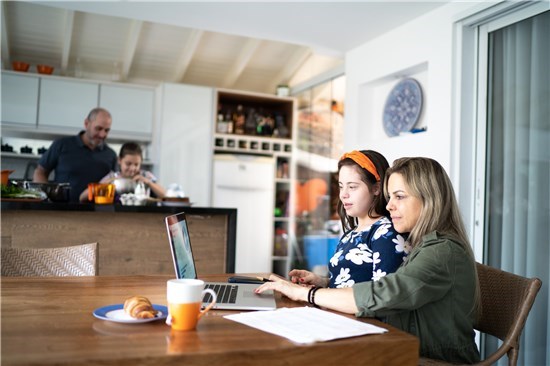 Woman and girl look at computer at breakfast