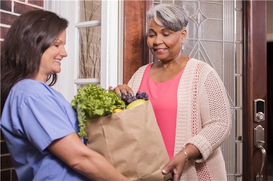 Woman receiving groceries from home health aide
