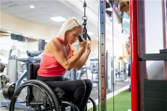 Woman in wheelchair using machine at gym