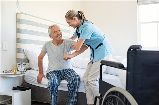 Man about to be moved from bed to wheelchair by home health aide